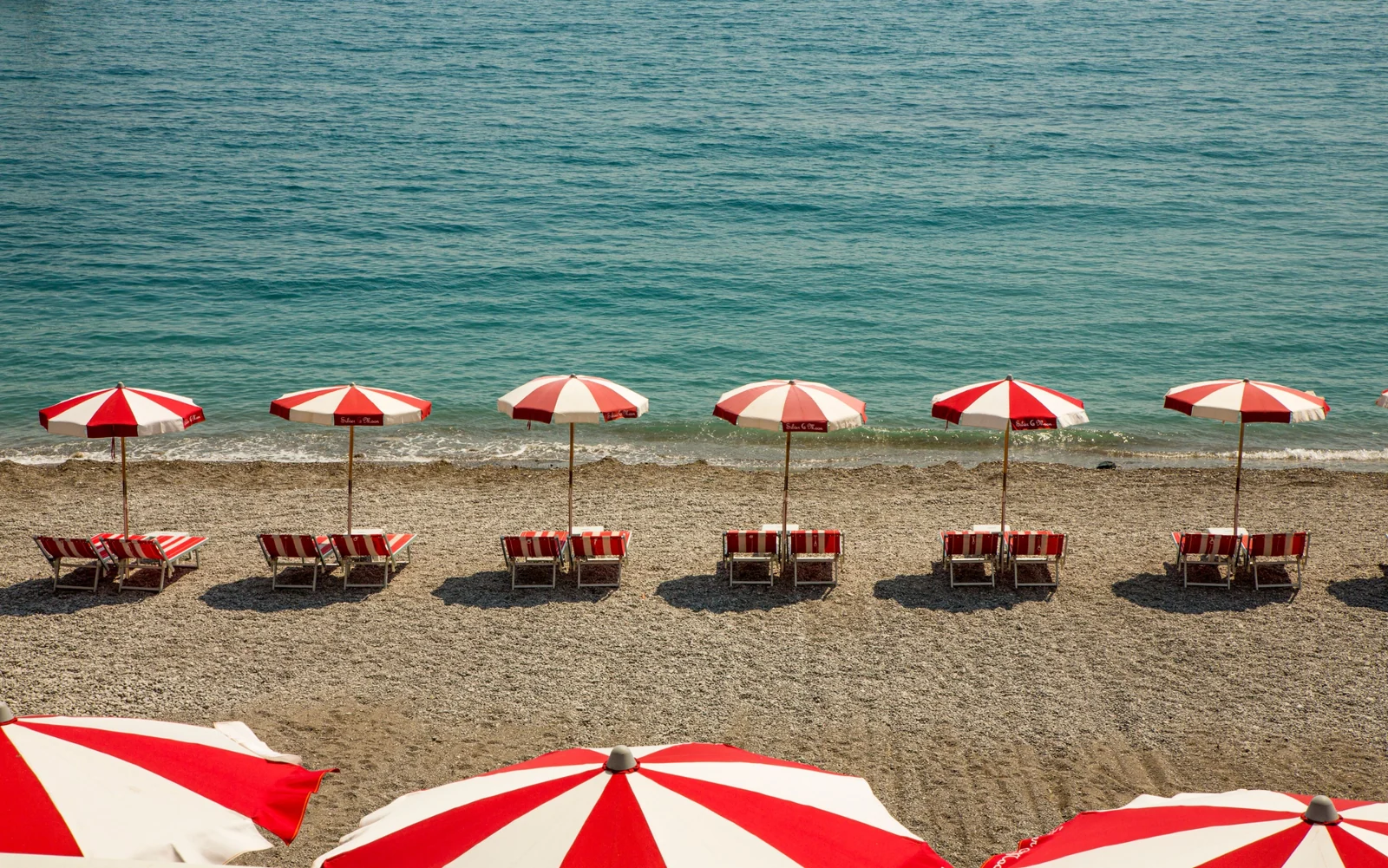 Ombrelloni rossi e bianchi e lettini sulla spiaggia davanti al mare