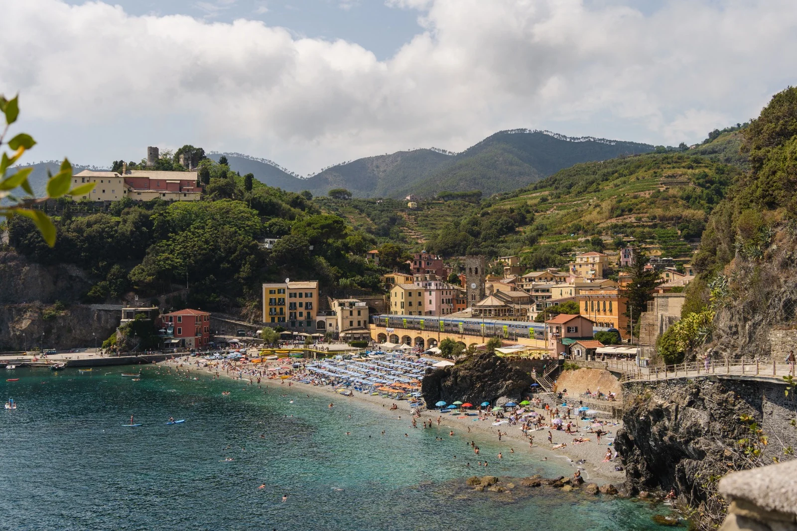 Baia con spiaggia, edifici costieri e colline verdi